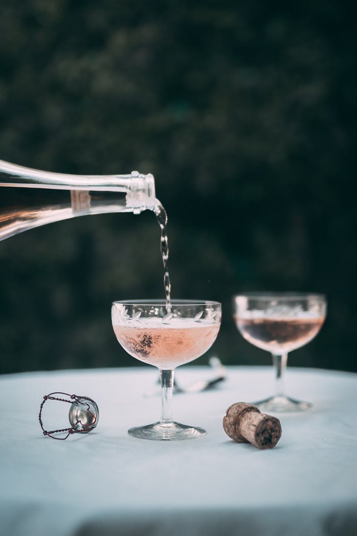 Champagne being poured into glasses on a table with cork and wire, creating an elegant setting.